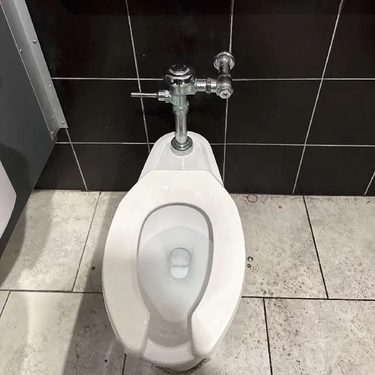 Close-up of commercial toilet connection and flush valve setup inspected during plumbing service in Tahlequah, OK