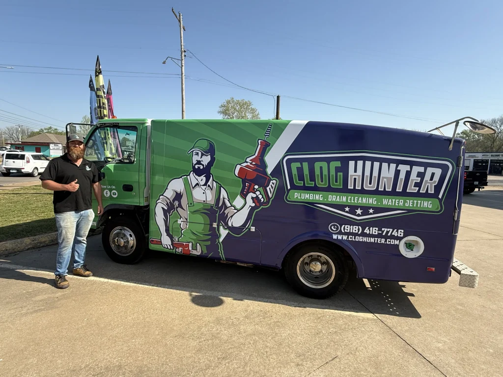 Clog Hunter's owner standing beside a wrapped plumbing truck in Tahlequah, Oklahoma